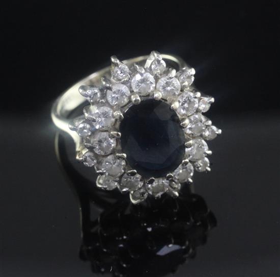 An 18ct white gold, sapphire and diamond oval cluster ring, size K.